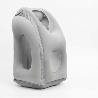 A clean, three-quarter angle product shot of the Alphinea inflatable air pillow in a soft grey color. The image showcases the skin-safe, breathable fabric and structural neck support designed to keep the airway open during upright travel.