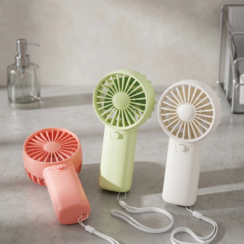 Group of three Alphinea lightweight AA battery pocket fans in various colors standing on a bathroom counter.