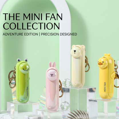The Alphinea mini fan collection displayed on clear acrylic risers, showcasing the pocket-sized travel fans in green, pink, cream, and yellow animal designs.