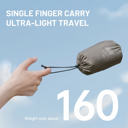 Une main tenant d'un seul doigt l'oreiller de voyage ultraléger Alphinea de 160 g dans sa pochette de rangement, illustrant sa portabilité maximale pour la randonnée.
