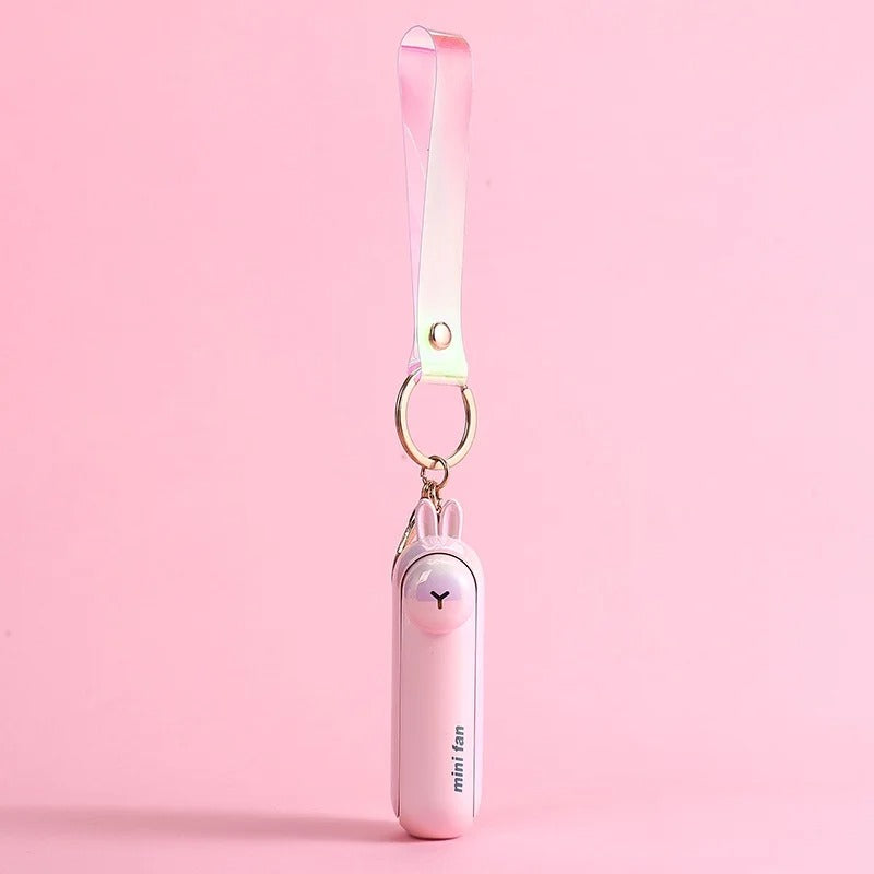 Pink rabbit design of the Alphinea USB rechargeable mini fan hanging by a matching pink lanyard against a soft pink background.