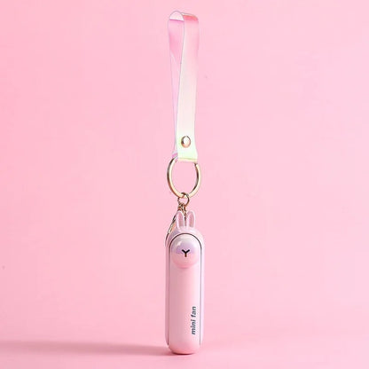 Pink rabbit design of the Alphinea USB rechargeable mini fan hanging by a matching pink lanyard against a soft pink background.